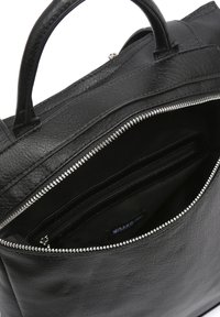 Bolso tote de piel negra con asas superiores, con cierre de cremallera y compartimentos interiores. Acabado texturizado y detalles de hardware en tono plata.