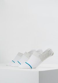 Drei Paar niedrig geschnittene Socken ausgestellt. Die Socken sind weiß mit grauen und türkisfarbenen Akzenten, haben eine strukturierte Oberseite und ein Logodetail.