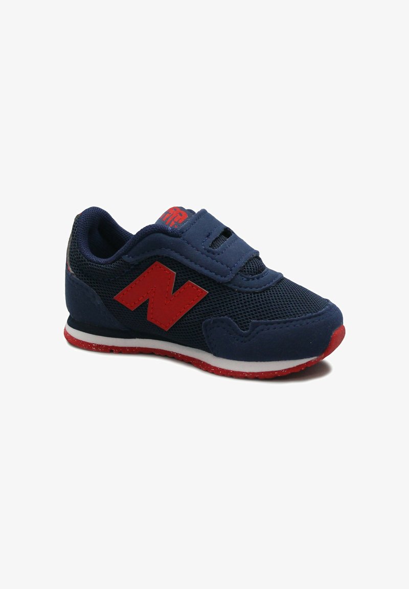 Basket enfant bleu marine avec logo "N" rouge, semelle extérieure rouge, semelle intermédiaire blanche et fermeture à scratch.