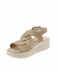 Sandali con zeppa beige decorati con strass, punta open toe, cinturini incrociati e cinturino regolabile sul retro. Interno morbido per il massimo comfort.