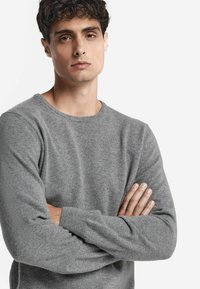 Szary sweter z dzianiny o okrągłym dekolcie, długich rękawach i miękkiej teksturze, dopasowany blisko ciała, z prążkowanymi mankietami i dołem.