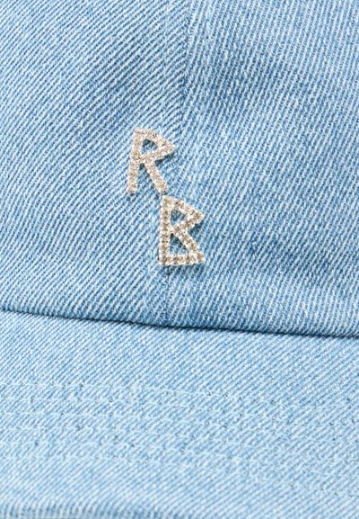 Ανοιχτό μπλε ύφασμα τζιν με δύο γράμματα από στρας, "R" και "B", πιθανόν μέρος ενός αξεσουάρ ρούχου ή λεπτομέρειας ένδυσης.