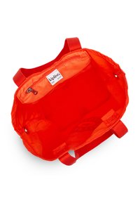 Interno di una borsa rossa in nylon con una tasca con zip e due tasche aperte; texture liscia con un'etichetta del marchio all'interno. Progettata per un uso leggero.