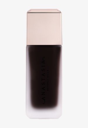 Botella cosmética marrón oscuro con base de vidrio esmerilado y tapa rectangular brillante de oro rosa, etiquetada "Anastasia Beverly Hills."