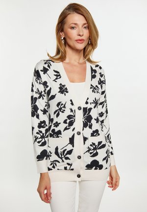 Cardigan ușor, cu o bază crem și un model floral negru, cu buton în față și două buzunare frontale. Mâneci lungi cu manșete ribbate.