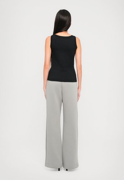 Fekete ujjatlan felső világosszürke, bő szárú nadrággal párosítva. Mindkettő puha anyagból készült, hangsúlyozva a laza illeszkedést és a letisztult vonalakat.