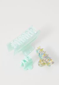 Set di fermagli per capelli in materiali trasparenti di colore verde menta e iridescenti. Include tre dimensioni; presenta forme curve e design a scanalature.