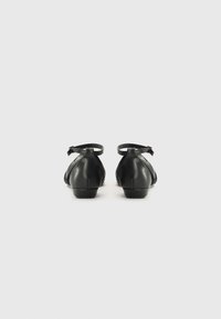 Zwarte leren balletschoenen met een lage hak en enkelbandje, met een gladde textuur en een rond neusdesign.