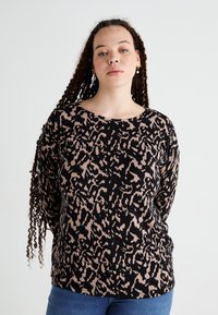 Svart långärmad topp med beige abstrakt djurmönster, rund halsringning och avslappnad passform. Tillverkad av ett mjukt, texturerat tyg.