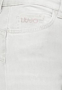 Białe szorty dżinsowe o klasycznym kroju, z fakturowaną powierzchnią, lekkim rozciąganiem oraz małym, haftowanym logo marki na kieszeni.