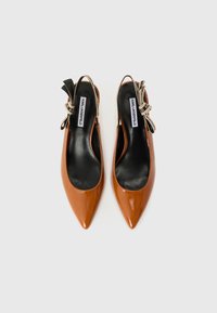 Chaussures slingback en cuir verni marron avec des pointes pointues, des semelles intérieures noires et une sangle décorative noire arborant un logo beige.