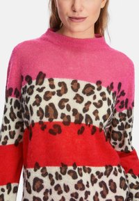 Farbblockierter Pullover mit rosa, rotem und cremfarbigem Streifenmuster sowie einem Leopardenmuster. Hergestellt aus einem weichen, strukturierten Stoff mit hohem Kragen.
