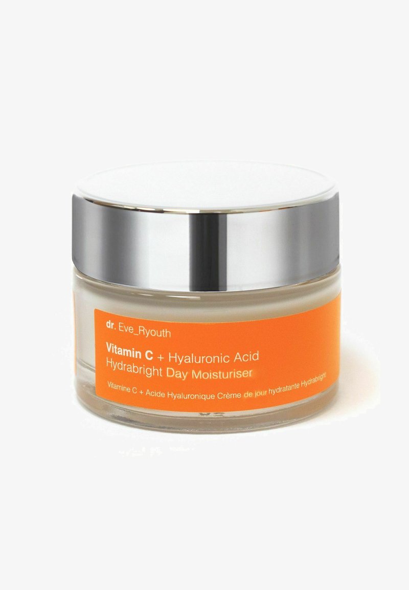 Clear glass jar with a silver lid; orange label text reads "Vitamin C + Hyaluronic Acid Hydrabright Day Moisturiser." Creamy texture visible.
