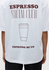 Baltas marškinėliai su bordo spalvos tekstu "ESPRESSO SOCIAL CLUB" ir "ESPRESSO ME UP", o centre pavaizduota kontūrinė puodelio grafika.