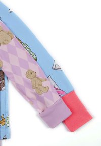 Pijama de manga larga en suave algodón. Sección azul con gráficos de dibujos animados, rombos morados y un puño rosa. Presenta un oso de peluche y diseños juguetones.