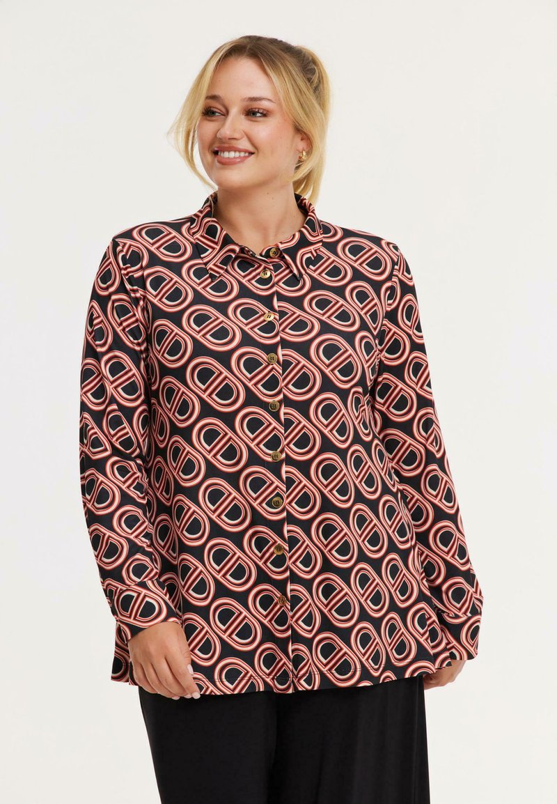 Schwarze Hemdbluse mit ovalem Muster in Rot und Weiß. Lange Ärmel, Kragen und goldene Knöpfe unterstreichen das Design.
