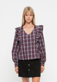 Pruimen geruite blouse met gerimpelde mouwen, V-hals en lange mouwen. Gecast met een zwarte corduroy rok met knopen aan de voorkant.