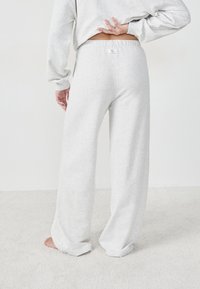 Hellegraue, weiche Stoff-Hosen mit weitem Bein, elastischem Bund und hochgerollten Säumen, versehen mit einem kleinen Markenetikett auf der Rückseite.