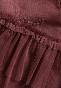 Burgunderfarbener Tule-Stoff mit transparenter Textur, der zarte Blumenstickereien und geraffte Rüschen entlang des Randes aufweist.