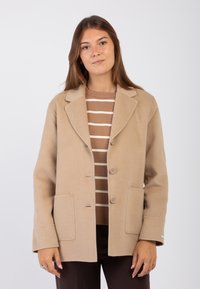 Giacca in misto lana beige con colletto a punte, due tasche frontali e chiusura a bottoni. Il design presenta una vestibilità comoda e un orlo dritto.