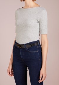 Šedý top s krátkým rukávem a širokým výstřihem, v kombinaci s tmavomodrými džíny a černým opaskem se zlatou kulatou sponou.