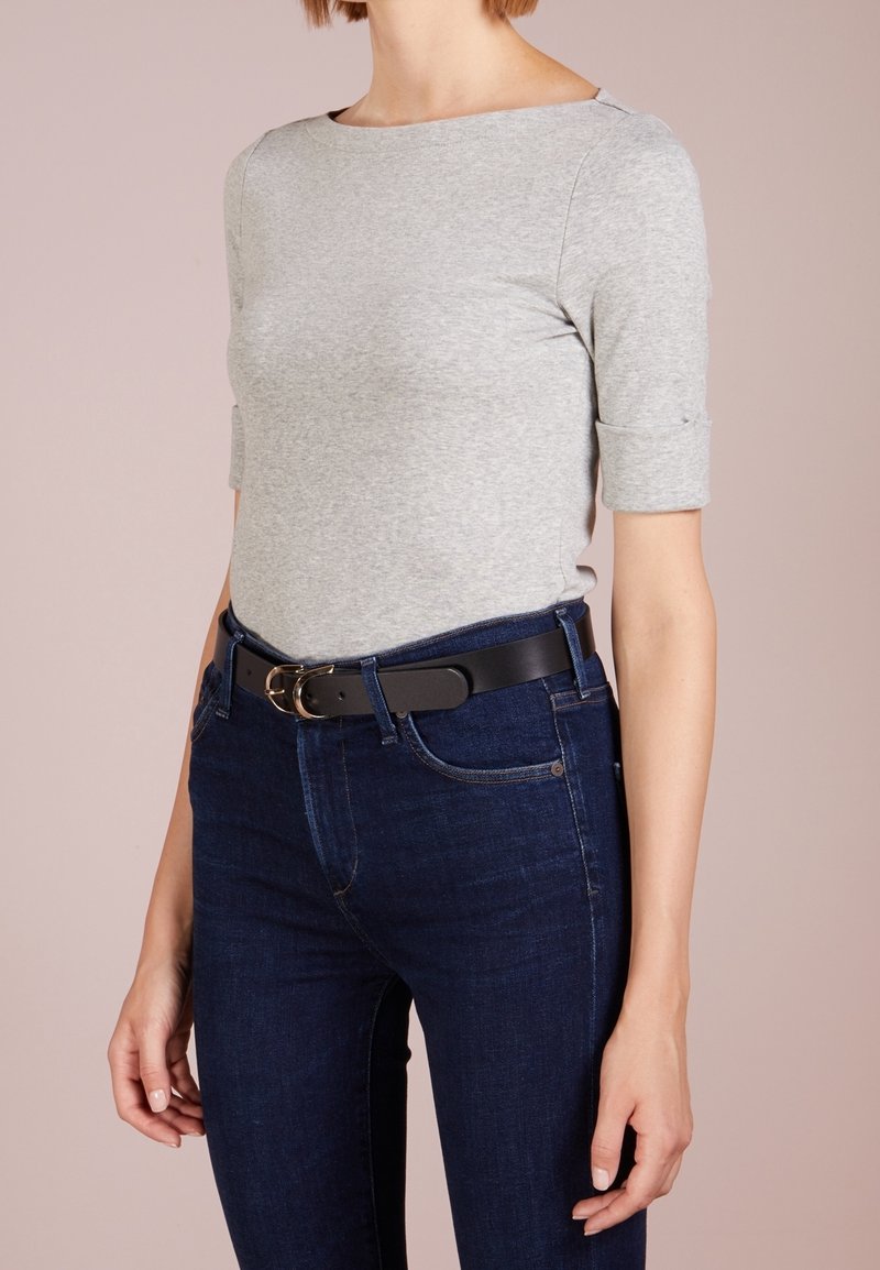 Šedý top s krátkým rukávem a širokým výstřihem, v kombinaci s tmavomodrými džíny a černým opaskem se zlatou kulatou sponou.