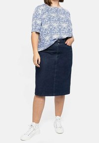 Blautopf-mustered kurzärmliges Oberteil, kombiniert mit einem dunkelblauen Jeans-Bleistiftrock. Das Outfit hat eine hohe Taille und ein minimalistisches Design, ergänzt durch weiße Sneaker.