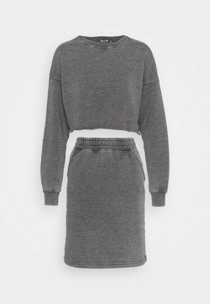 Ciemnoszara, długorękawowa, krótka bluza ze surowym wykończeniem u dołu, zestawiona z dopasowaną spódnicą z elastycznym pasem i bocznymi kieszeniami.