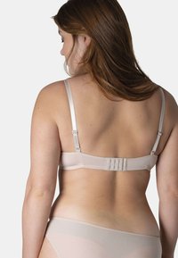 Soutien-gorge beige avec bretelles satinées réglables, fermeture à agrafes, et tissu lisse. Présente un design minimaliste avec une texture légère.