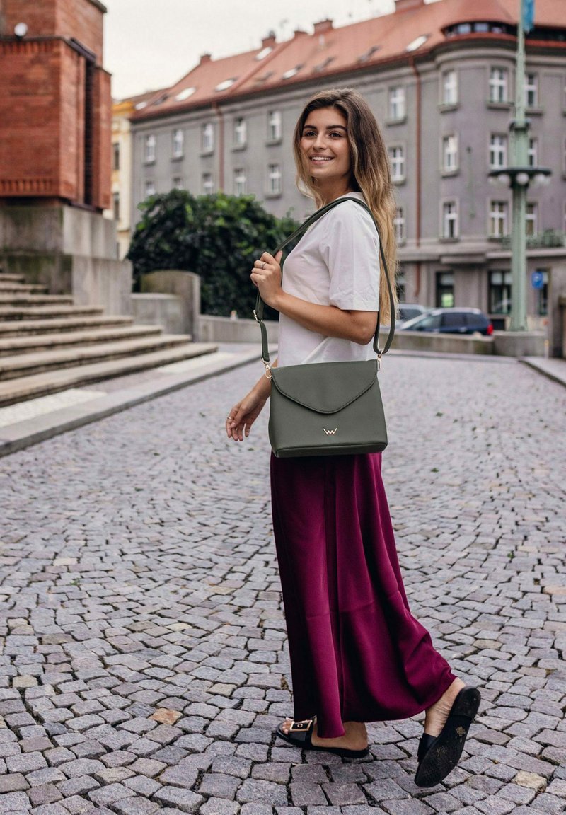 Šedá crossbody taška s klopou, kožený materiál, minimalistický design a detaily s logem. Létající vínová sukně a ploché boty.