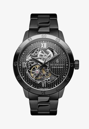 Montre automatique noire avec un boîtier transparent révélant des engrenages complexes. Cadran en fibre de carbone texturée avec chiffres romains et bracelet en métal.
