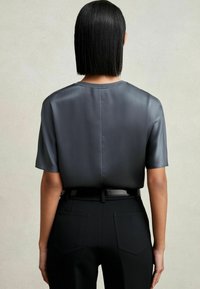 Top in satin grigio scuro a maniche corte, con scollatura a girocollo, texture liscia, forma aderente, abbinato a pantaloni neri su misura e una cintura nera.