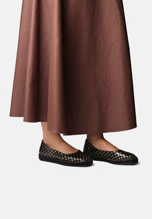 Črne balerinke z zlatim vzorcem zakovic, zaobljenim sprednjim delom in strukturirano površino, kombinirane z rahlo rjavno krilo. Ravna gumijasta podplat.