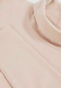 Pulover roz deschis cu guler înalt, realizat dintr-un material moale. Dispune de un guler rotund și o buzunar pe față. Textură netedă, design minimalist.