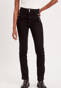 Jean noir taille haute avec fermeture à cinq boutons, coupe slim et poches latérales. Fabriqué en toile de denim avec une texture lisse.