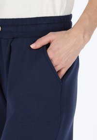 Marineblauwe joggingsbroek met een elastische waistband en zijzakken, vervaardigd uit een soepele, lichte stof en met een relaxte pasvorm.