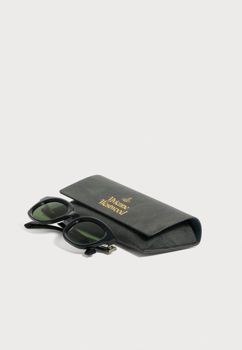 Occhiali da sole rettangolari neri con lenti verdi accanto a un astuccio morbido nero marchiato Vivienne Westwood su sfondo bianco.