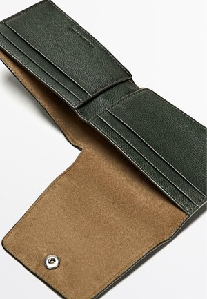 Green leather wallet with a textured exterior, features multiple card slots and a smooth beige suede interior. Snap closure detail visible.
