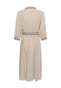 Robe longue beige à manches 3/4, avec bordure noire en zigzag sur le col, les poignets, les épaules, et une ceinture assortie, vue de dos.