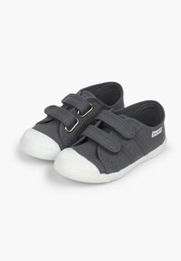 Zapatillas de lona grises con suelas de goma blanca, que presentan un upper texturizado y dos correas ajustables de Velcro para un ajuste seguro.