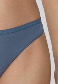 Blauer Bikini-Unterteil aus glattem Stoff mit einem nahtlosen Bund und minimalistischer Gestaltung. Leicht strukturierte Oberfläche, tiefer Schnitt.