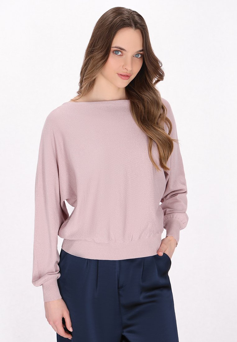 Lichtroze lange mouwen pullover met een bootkraag en een geribde zoom. Heeft een zachte textuur en een ontspannen pasvorm, gecombineerd met donkerblauwe broek.