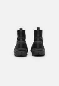 Black athletic shoes with a sock-like design, knit upper, and textured rubber sole. Includes pull tabs and contrasting side accents.