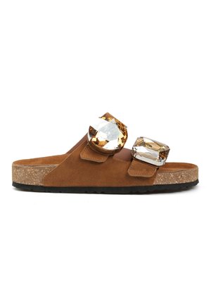 Brązowy zamszowy sandał typu klapki z korkową podeszwą i dwoma dużymi klamrami z bursztynowymi kamieniami na górnych paskach.