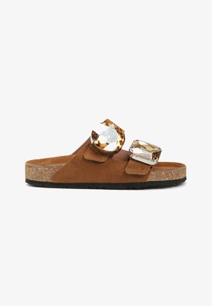 Brązowy zamszowy sandał typu klapki z korkową podeszwą i dwoma dużymi klamrami z bursztynowymi kamieniami na górnych paskach.