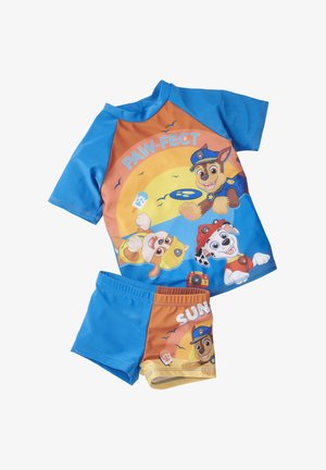 Set da bagno per bambini blu e arancione, composto da una maglietta a maniche corte e pantaloncini, caratterizzato da personaggi di cani dei cartoni animati. Il materiale sembra morbido e leggero.