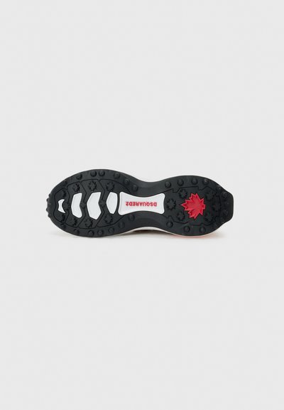 Sole in gomma nera con tacchetti, caratterizzata da un'etichetta bianca e un logo a foglia rossa. Forma ergonomica con scanalature multidirezionali per una migliore aderenza.