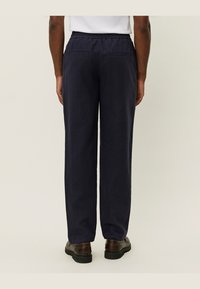 Pantaloni relaxați de culoare bleumarin, cu talie elastică, două buzunare la spate și o textură de material ușor.