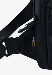 Black Cordura fabric shoulder bag with adjustable strap, featuring a black plastic clip and visible brand label, textured finish.