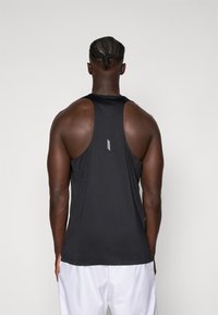 Svart atletisk tank topp med racerback-design, laget av lett materiale med en subtil tekstur. Lite logo detalj på ryggen.